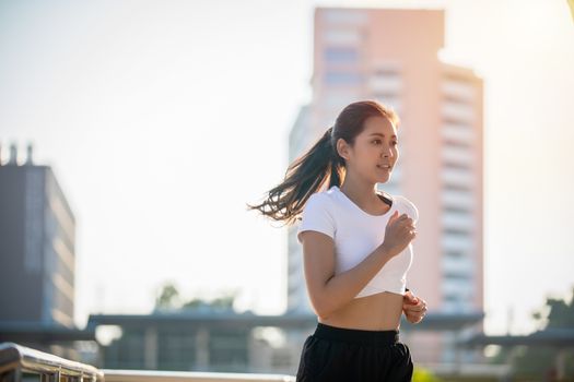 Asian Young fitness sport woman running  and smiling on city road