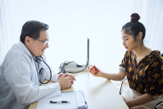 The doctor is asking and explaining the illness and giving the medicine. With female patients in his office at the hospital.