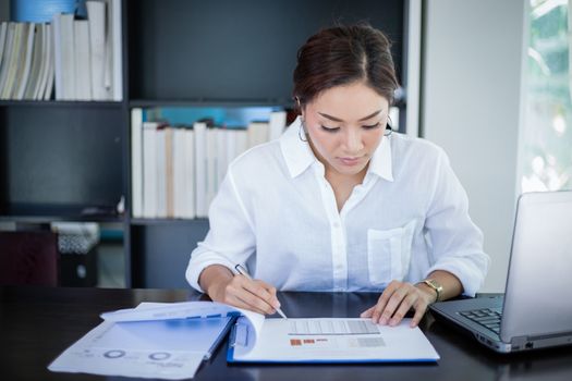 beautiful Asian business women checking document and using notebook and smiling happy for working