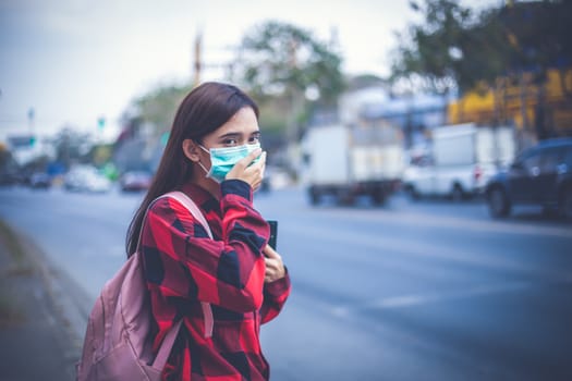 Asian Young woman walking in the city wearing face mask because of air pollution, particulates and for protection flu virus, influenza, coronavirus