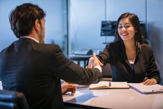 Business people shaking hands and smiling their agreement to sign contract and finishing up a meeting
