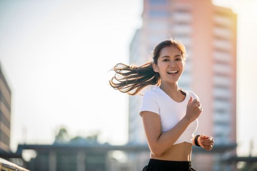 Asian Young fitness sport woman running  and smiling on city road