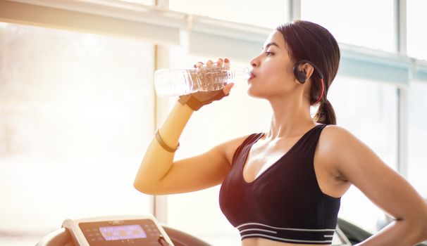 Sporty woman asia drinking water after exercises in the gym. Fitness - concept of healthy