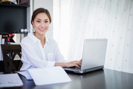 beautiful Asian business women checking document and using notebook and smiling happy for working
