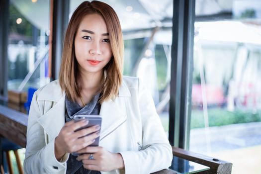 woman asian using phone for shopping online and calling with cell telephone in coffee shop during free time