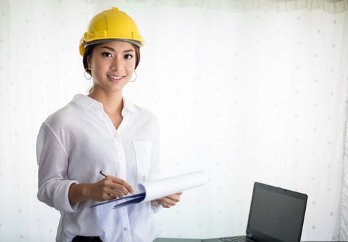 Asian women engineering inspecting and working and holding blueprints at office