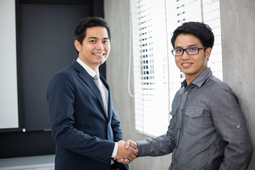 Asian Business people shaking hands and smiling their agreement to sign contract and finishing up a meeting
