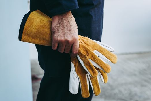 Close-Up of Mechanic Technician Hand is Holding Leather Gloves While Standing in front of Maintenance Workshop, Technical Service Worker Preparation for Fixing Automotive in Workshops House.
