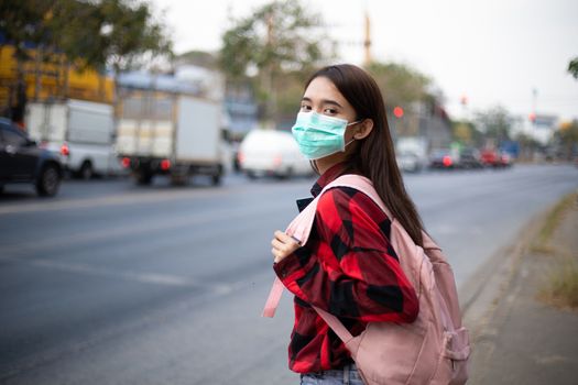 Asian Young woman walking in the city wearing face mask because of air pollution, particulates and for protection flu virus, influenza, coronavirus