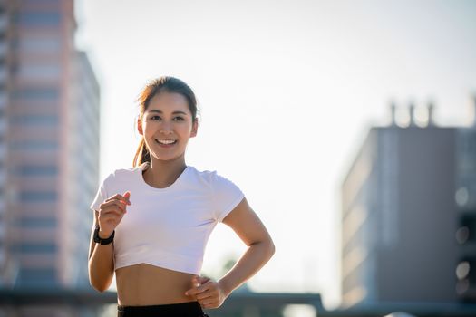 Asian Young fitness sport woman running  and smiling on city road