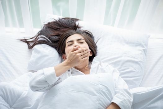 Asian woman Beautiful young smiling woman sitting and sleeping in white bed and stretching in the morning at bedroom after waking up in her bed fully rested
