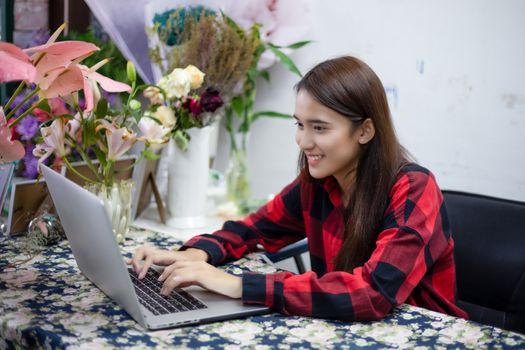 Asian women florists using notebook for working in flower shop