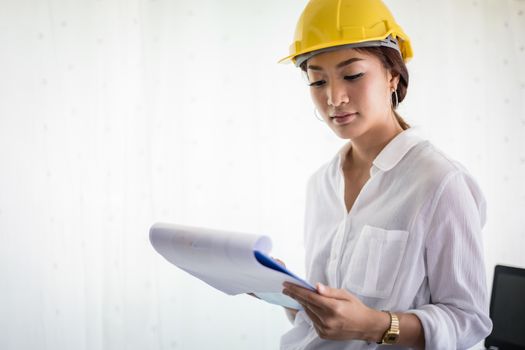 Asian women engineering inspecting and working and holding blueprints at office