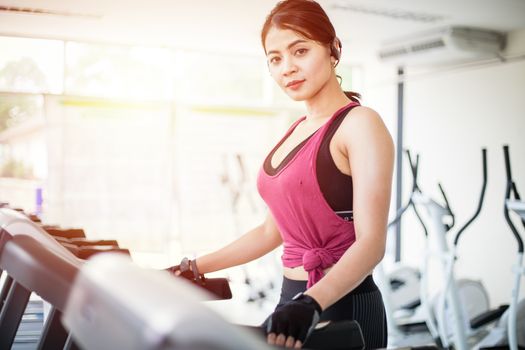 Asian women running sport shoes at the gym while a young caucasian woman is having jogging on the treadmill
