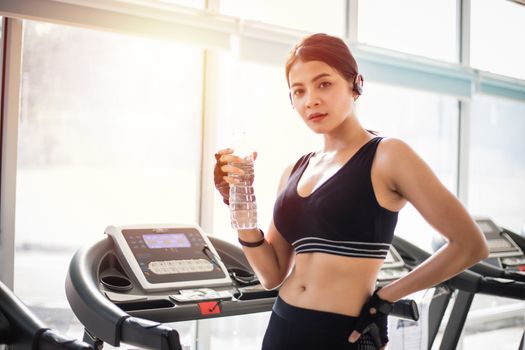 Sporty woman asia drinking water after exercises in the gym. Fitness - concept of healthy