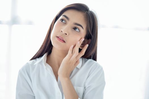 A beautiful woman asian using a skin care product, moisturizer or lotion taking care of her dry complexion. Moisturizing cream in female hands .