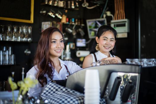 Asian women Barista smiling and using coffee machine in coffee shop counter - Working woman small business owner food and drink cafe concept