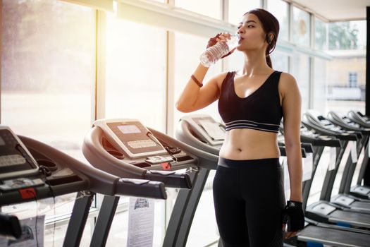 Sporty woman asia drinking water after exercises in the gym. Fitness - concept of healthy