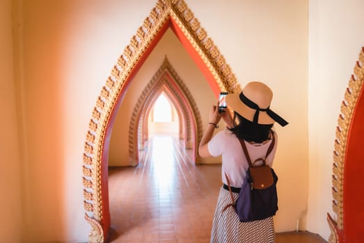 Tourist Woman Having Fun While Sightseeing in The Temple, Asian Woman Relaxing and Enjoyment While Photographing Statue of Buddha With Art Ancient Architecture in Religion Worship. Travel Exploring