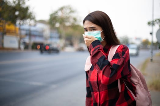 Asian Young woman walking in the city wearing face mask because of air pollution, particulates and for protection flu virus, influenza, coronavirus