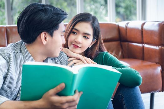 Portrait of Young Couple Love in Romantic Emotions While Reading a Book Together, Couple Young People Having Fan and Relaxing in Living Room. Happy Emotion and Relaxation Lifestyles Concept