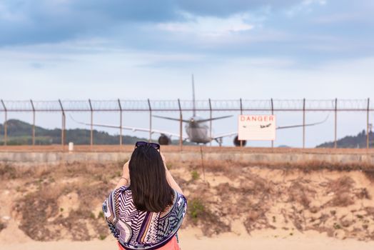 Portrait of Beautiful Woman is Capturing Photos The Airplane While Take off Landing on Runway Track. Tourist Woman Having Fun With Photographic Vehicle Aircraft Beside The Airport Fence. Travel Danger