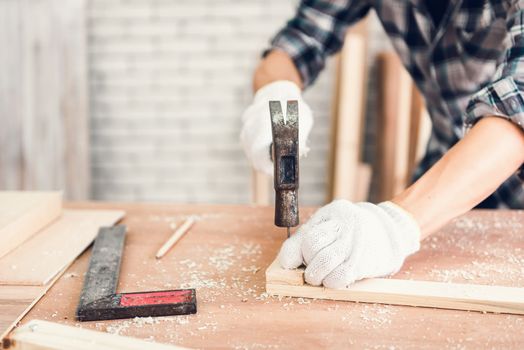 Carpenter Man is Working Timber Woodworking in Carpentry Shop, Craftsman is Hammering a Nail into Timber Frame for Wooden Furniture in Workshop. Workmanship and Job Occupation Concept