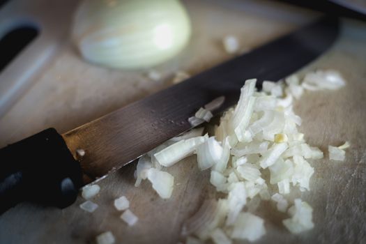 woman cuts onions on a white plastic board in a kitchen