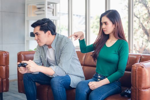 Portrait of Woman Feeling Offended With Her Boyfriend When He Playing Video Games While Sitting on The Couch in Living Room. Couple Love Relationship and Lifestyles Concept.