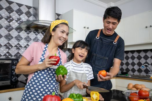 Happy Family have Dad, Mom and their little daughter Cooking Together in the Kitchen