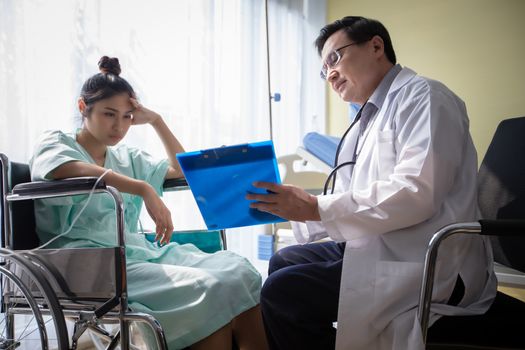 The doctors are asking and explaining about the illness to a female patient on wheelchair at a hospital