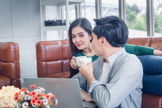 Couple Love Having Relaxation Discussing While Drinking a Coffee in Their Home, Attractive Asian Couple Happiness in Romantic Moments at Living Room. Relaxing and Lifestyles Concept