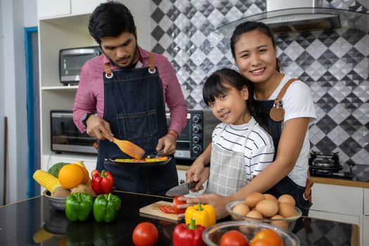 Happy Family have Dad, Mom and their little daughter Cooking Together in the Kitchen