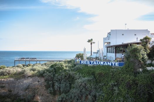 Albufeira, Portugal - May 3, 2018: People enjoying the sea view from the pontoon of a restaurant overlooking the beaches on a spring day