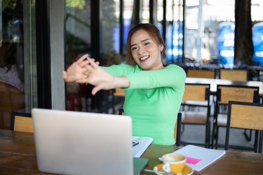 Asian woman stretching after reading book and work hard and smiling in coffee shop