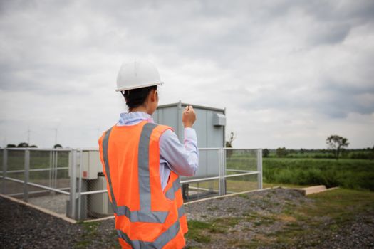 Asian engineer with hardhat using  tablet pc computer inspecting and working at wind turbine farm Power Generator Station