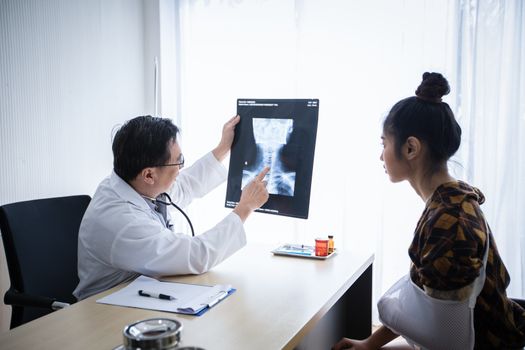 The doctor is explaining about the brain X-ray results to a female patient lying in bed at a hospital