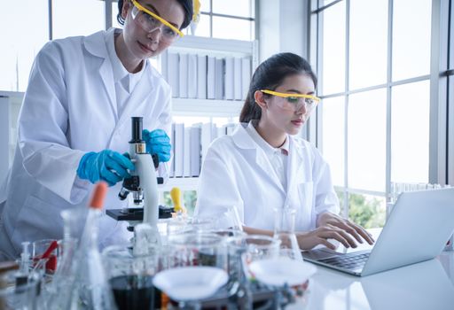 Medical Research and Scientists are working with a microscope and a tablet and Test Tubes, Micropipette and Analysis Results in a laboratory.
