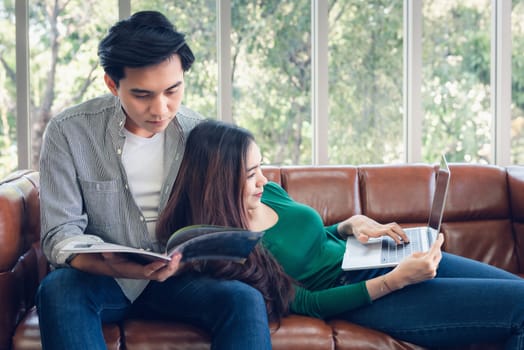 Couple Love Having Enjoy Relaxation on Sofa at Their Home, Attractive Asian Couple Happiness in Romantic Moments at Living Room While Reading Magazine and Work at Home. Relaxing and Lifestyles Concept