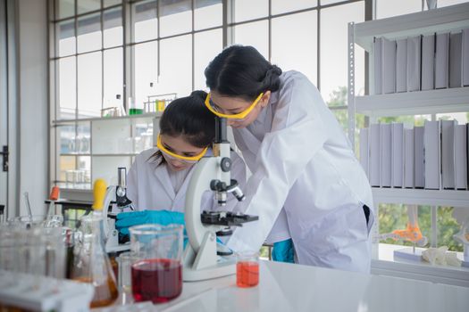Medical Research and Scientists are working with a microscope and a tablet and Test Tubes, Micropipette and Analysis Results in a laboratory.
