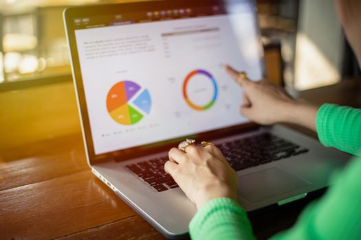 Asian businesswomen using notebook for analysis documents and graph financial diagram working