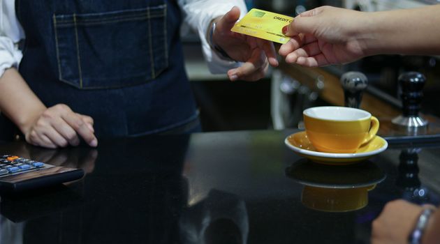 Barista serving customer and Woman is paying for coffee by credit card in coffee shop