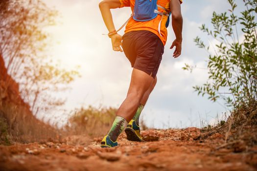 A man Runner of Trail and athlete's feet wearing sports shoes for trail running in the mountain