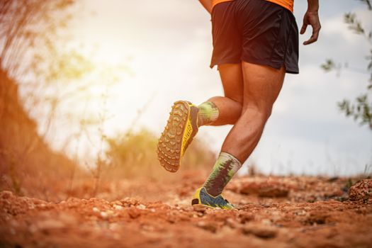 A man Runner of Trail and athlete's feet wearing sports shoes for trail running in the mountain