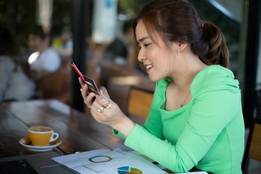 Asian women drinking coffee in a cafe and shopping online and paying with credit card on smart phones