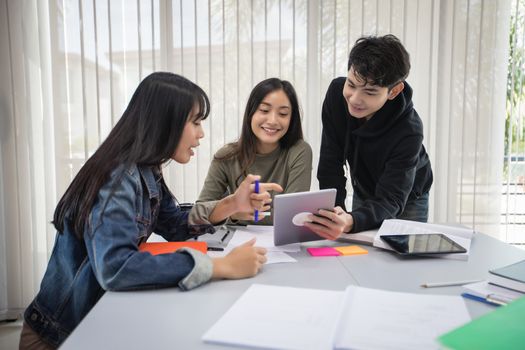 Group Asian  Students Smile and reading book and using notebook for helps to share ideas in the work and project. And also review the book before the exam