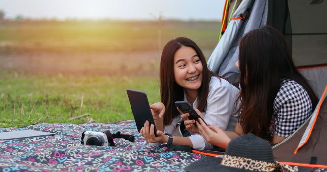 A group of Asian friends playing Ukelele and spending time making a picnic in the summer holidays.They are happy and have fun on holidays. They using notebook for working