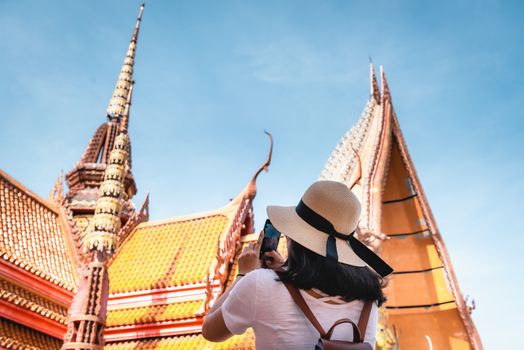 Tourist Woman Having Fun While Sightseeing in The Temple, Tourist Woman Relaxing and Enjoyment While Photographing Statue of Buddha With Art Ancient Architecture in Religion Worship. Travel Exploring