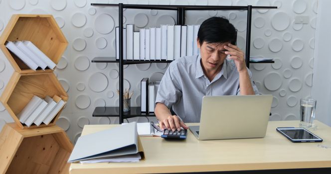 A senior Asian man using notebook for working and businesswoman serious about the work done until the headache