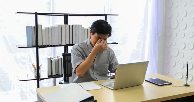 A senior Asian man using notebook for working and businesswoman serious about the work done until the headache